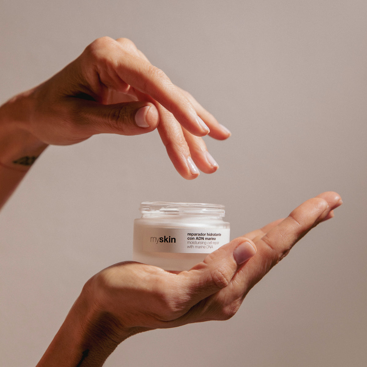Reparador hidratante con ADN marino de myskin Barcelona en tarro de 50 ml, sostenido entre las manos durante una rutina de cuidado facial.